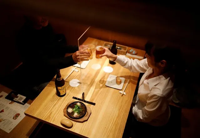 Customers toast beers across plastic transparent board on a table installed as a measure to prevent an infection with the coronavirus disease (COVID-19) at Kichiri Shinjuku, a Japanese style pub known as an “izakaya”, in Tokyo, Japan on May 19, 2020. (Photo by Issei Kato/Reuters)