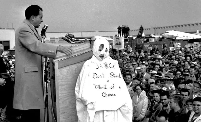 Vice President Richard M. Nixon addresses a crowd at Chicago's O'Hare Airport, October 29, 1960, while campaigning for president against Sen. John F. Kennedy. Next to him stands 10-year-old Tom Lemke, wearing a Halloween ghost costume that reads “Jack Don't Stand a Ghost of a Chance”, referring to John F. Kennedy. When Nixon spotted to boy in the crowd, he called attention to the youngster. (Photo by AP Photo)
