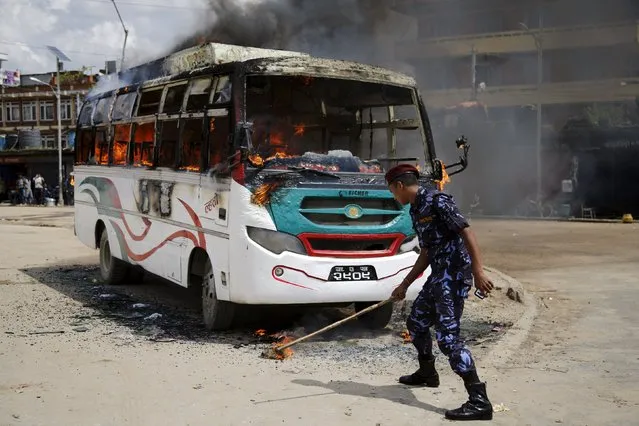 A Nepalese police tries to douse fire set by unidentified protesters on a passenger bus during the nationwide strike, called by the opposition parties against the proposed constitution, in Kathmandu, Nepal September 20, 2015. (Photo by Navesh Chitrakar/Reuters)