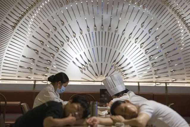 Restaurant workers nap on tables at a restaurant in a mall in Beijing on Wednesday, July 15, 2020. Small businesses around the world are fighting for survival amid the economic fallout from the coronavirus pandemic. Whether they make it will affect not just local economies but the fabric of communities. (Photo by Ng Han Guan/AP Photo)