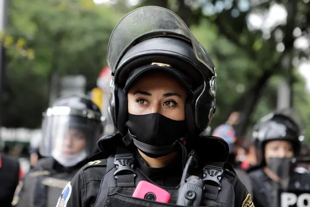 Police women stand guard during in march demanding justice for the victims of gender violence and femicides in Mexico City, Mexico on August 16, 2020. (Photo by Raquel Cunha/Reuters)