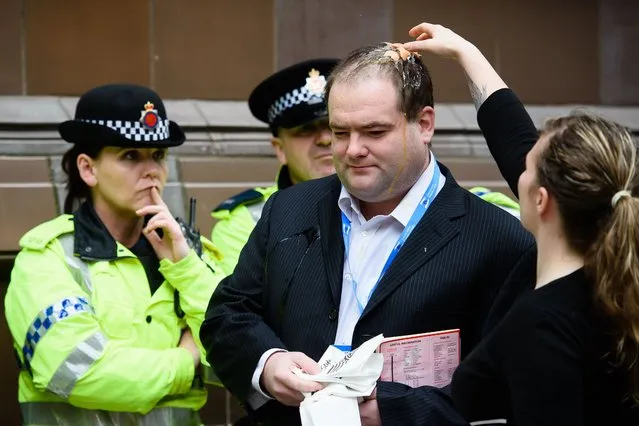 A conference attendee talks to police officers after being hit by an egg thrown by protestors on the second day of the annual Conservative party conference in Manchester, north west England, on October 5, 2015. (Photo by Leon Neal/AFP Photo)