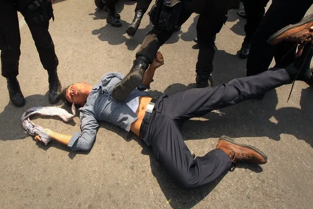 A police and soldiers subdue a demonstrator following clashes between police and demonstrators in Makassar located in South Sulawesi province, protesting the visit of Indonesian President Joko Widodo and denounced the government plan to cut huge fuel subsidies blamed for a widening current account deficit. Hundreds of students staged the protest as Widodo arrived for a two day working visit. (Photo by Yusuf Wahil/AFP Photo)