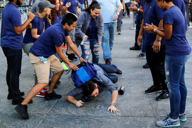 Apple workers assist a customer who fell down before going into the Apple Inc. during the sale of the iPhone 7 smartphone in New York, U.S., September 16, 2016. (Photo by Eduardo Munoz/Reuters)