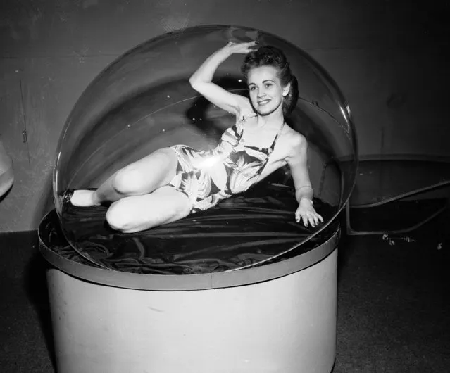 Model Gladys McDaniel adds a bit of glamour to this exhibit of molded transparent plexiglas as she poses under a dome of the material at the third annual meeting of the Society of Plastics Engineers, in Chicago, Ill., February 2, 1947. The plexiglas, which is used in the manufacturing of airplanes, is made by the Fabri-Form Company of Byesville, Ohio.  (Photo by Edward Kitch/AP Photo)