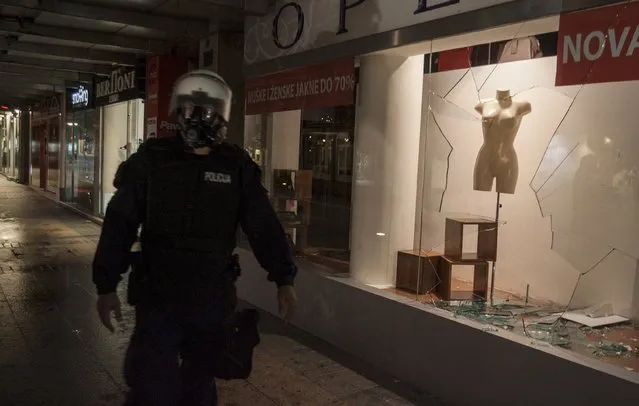 A riot policeman walks past a broken store window after protests in Podgorica, Montenegro, October 17, 2015. Montenegro's police used teargas on Saturday to disperse hundreds of anti-government protesters outside the parliament building in the capital Podgorica and local media said several people had suffered light injuries. (Photo by Stevo Vasiljevic/Reuters)