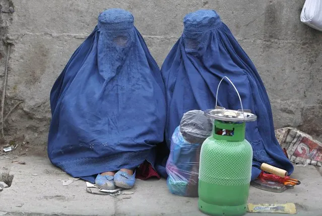 Afghan women sit along a street as they wait for transportation in Kabul March 19, 2013. (Photo by Omar Sobhani/Reuters)