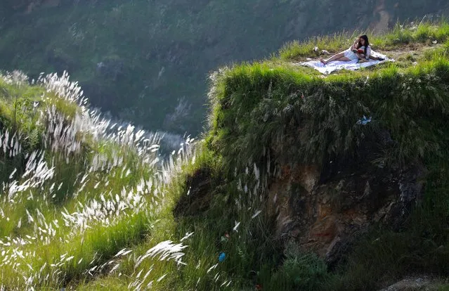 A woman reads a book at Chobhar a picnic spot in Kathmandu, Nepal on September 30, 2020. (Photo by Navesh Chitrakar/Reuters)