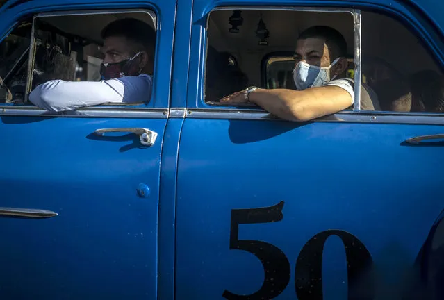 Wearing masks as a precaution against the spread of the new coronavirus people travel in a taxi in Havana, Cuba, Wednesday, October 14, 2020. (Photo by Ramon Espinosa/AP Photo)
