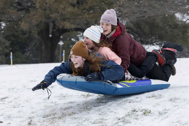 Claire Laviolette, left, 19, Jojo Kisser, center, 8, and Jaycee Kisser, 8, catch some air while sledding at Flag Pole Hill in Dallas, Tuesday, January 31, 2023. Freezing rain and sleet continue to fall across North Texas, covering roadways in ice. (Photo by Elías Valverde II/The Dallas Morning News via AP Photo)