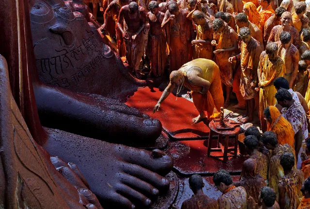 A devotee touches the feet of the monolithic statue of Jain god Gomateshwara as he celebrates the Mahamastakabhisheka, or head-anointing ceremony of the statue, in Shravanabelagola, India, February 18, 2018. (Photo by Abhishek N. Chinnappa/Reuters)
