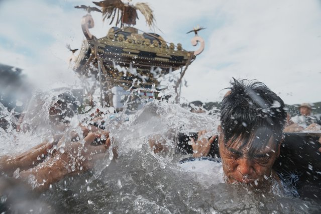 Participants carry a portable shrine, or mikoshi, into the sea during a purification rite at the annual Kurihama Sumiyoshi Shrine Festival at Kurihama, Yokosuka city, south of Tokyo Sunday, July 27, 2025. (Photo by Eugene Hoshiko/AP Photo)