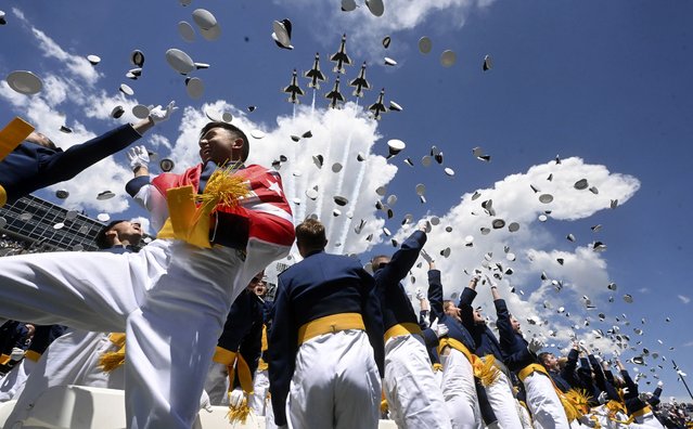 Cadet Jonathan Loh, left, from Singapore, and the class of 2024 at the United States Air Force Academy toss their hats in the air as the Thunderbirds fly over Falcon Stadium, Thursday, May 30, 2024, at the conclusion of the commencement ceremony in Colorado Springs, Colo. (Photo by Jerilee Bennett/The Gazette via AP Photo)