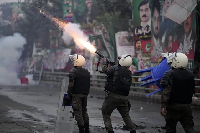A riot police officer fires tear gas to disperse supporters of former Prime Minister Imran Khan during clashes outside Khan's residence, in Lahore, Pakistan, Tuesday, March 14, 2023. Pakistani police scuffled with supporters of former Prime Minister Imran Khan as officers arrived outside his home to arrest him for failing to appear in court on graft charges, police and officials said. (Photo by K.M. Chaudary/AP Photo)
