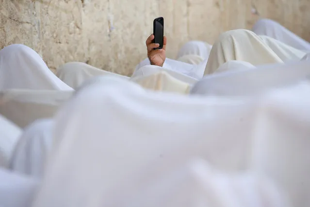 A Jewish worshipper uses his mobile phone to record worshippers who are covered in prayer shawls as they recite the priestly blessing at the Western Wall in Jerusalem's Old City during the Jewish holiday of Sukkot October 19, 2016. (Photo by Baz Ratner/Reuters)