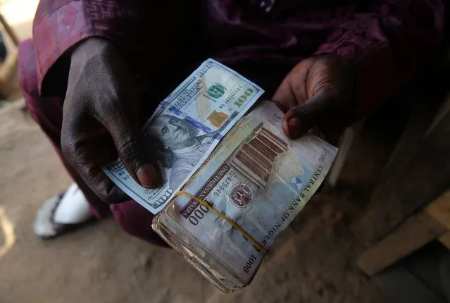 A money changer holds the Nigeria's Naira and a 100 US dollar note, along a street in Sapon district in Abeokuta, Nigeria, 11 December 2020. In the last weeks, the Nigerian currency has witnessed a monumental devaluation to the US dollars, especially in the black market and the prices of goods in the local market are astronomically high. (Photo by Akintunde Akinleye/EPA/EFE/Rex Features/Shutterstock)