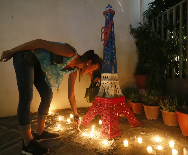 A French national lights candles in front of an Eiffel Tower replica outside the Alliance Francais during the memorial for the victims of Friday's Paris attacks Monday, November 16, 2015 at the financial district of Makati city, east of Manila, Philippines. Multiple attacks across Paris on Friday night have left more than one hundred dead and many more injured. (Photo by Bullit Marquez/AP Photo)