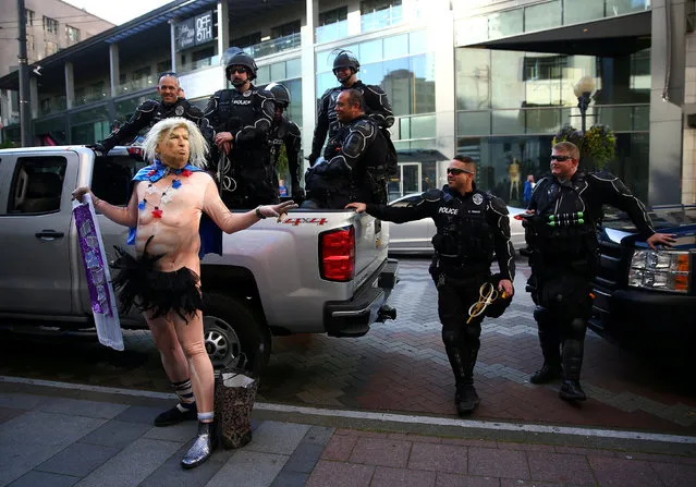 A man in a Trump outfit poses in front of a group of Seattle Police officers at Westlake Park on May Day in Seattle, Washington, U.S. May 1, 2018. (Photo by Lindsey Wasson/Reuters)
