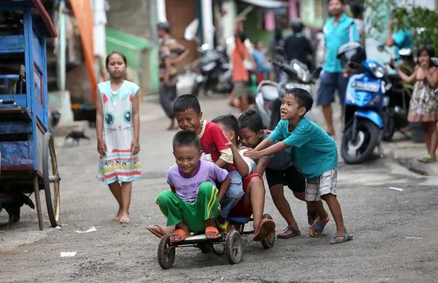 Children play a bicycle at a slum area in Jakarta, Indonesia, Tuesday, September 13, 2016, in Jakarta, Indonesia. (Photo by Tatan Syuflana/AP Photo)