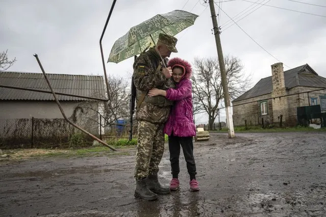 Khrystyna, 10 years old girl hugs a Ukrainian serviceman of 68 Oleksa Dovbush hunting brigade in Bohoyavlenka, Ukraine, on Sunday, April 9, 2023. Khrystyna's father died due to contusion after Russian shell hits his basement last summer. (Photo by Evgeniy Maloletka/AP Photo)