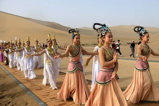 Performers showcase their clothes at Echoing Sand Mountain and Crescent Spring scenic area during the May Day holiday on May 1, 2023 in Dunhuang, Gansu Province of China. (Photo by Zhang Xiaoliang/VCG via Getty Images)
