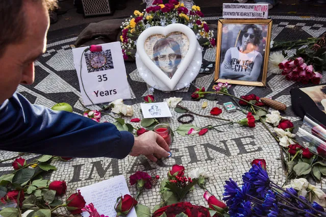 A fan of the late John Lennon places a pin a top the “Strawberry Fields” tile mosaic in Central Park, which was created in tribute to the musician, to mark the 35-year anniversary of his death on December 8, 2015 in New York City. Lennon was shot and killed by a gunman outside his apartment in the nearby Dakota building. (Photo by Andrew Burton/Getty Images)