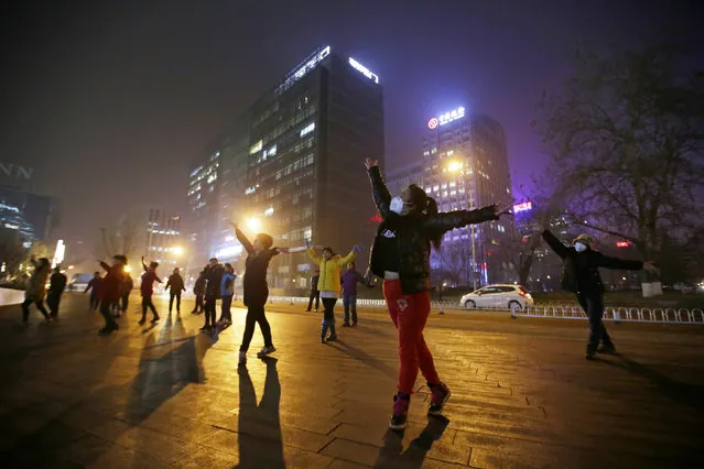 Women wearing masks and other residents dance during their daily exercise amid the heavy smog in Beijing, China December 7, 2015. China's capital on Monday issued its first ever "red alert" for pollution, as the city government warned that Beijing would be shrouded in heavy smog from Tuesday until Thursday. (Photo by Jason Lee/Reuters)