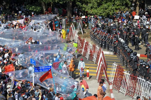People cover with plastic in case of a water canon use during a rally against the military coup and to demand the release of elected leader Aung San Suu Kyi, in Yangon, Myanmar, February 9, 2021. (Photo by Reuters/Stringer)