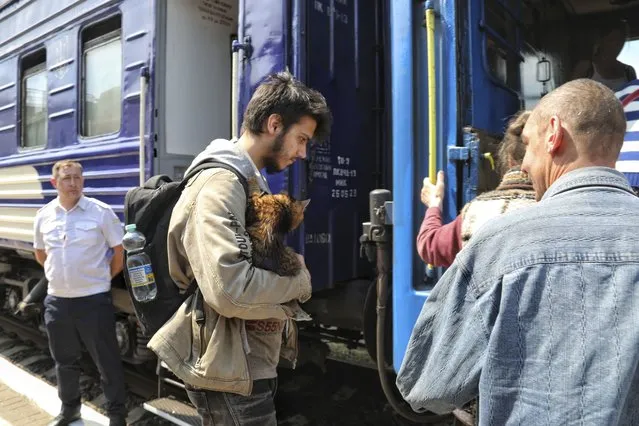 People board an evacuation train at a railway station in Kherson, Ukraine, Tuesday, June 6, 2023. Ukraine on Tuesday accused Russian forces of blowing up a major dam and hydroelectric power station in a part of southern Ukraine that Russia controls, risking environmental disaster. (Photo by Nina Lyashonok/AP Photo)