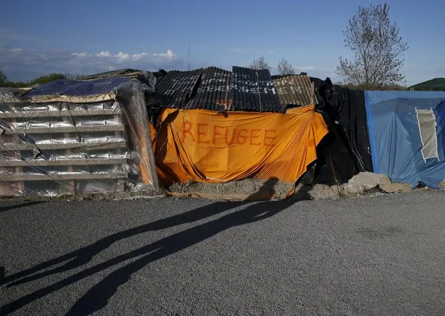 Shadows from migrants are cast on a makeshift shelter with the written word “Refugee” in Calais, France April 30, 2015. (Photo by Pascal Rossignol/Reuters)