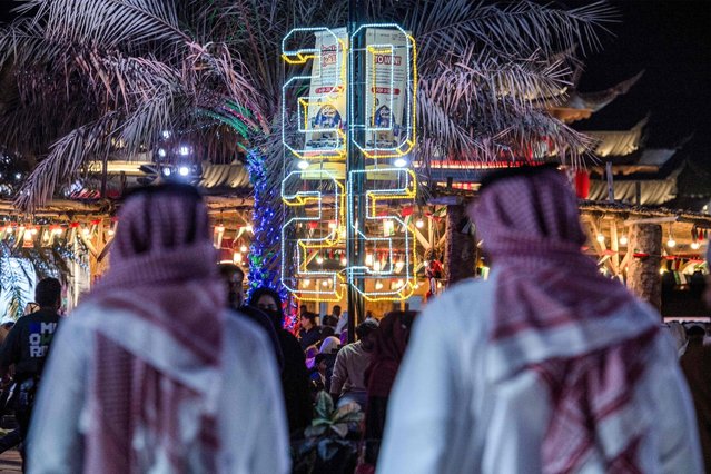 People walk at the Sheikh Zayed Heritage Festival as they await the New Years Eve fireworks and drone show in Abu Dhabi on December 31, 2024. (Photo by Ryan Lim/AFP Photo)