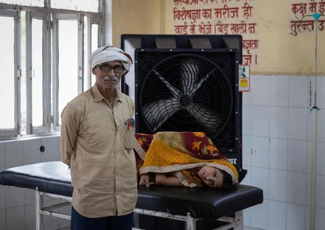 Reshmi Pathak, 30, who is suffering from heat-related illness, lies on a stretcher as her father stands next to her inside an emergency ward at a hospital in Ballia District in the northern state of Uttar Pradesh, India on June 21, 2023. (Photo by Adnan Abidi/Reuters)