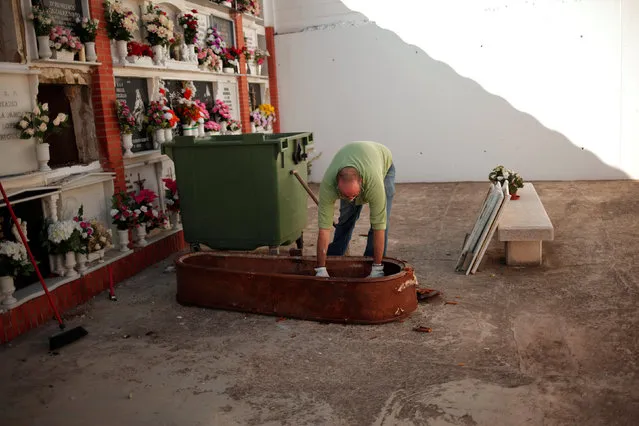 Unemployed Francisco Pimentel, 37, breaks a coffin after exhuming a body from a niche while he is observed by examiners (not pictured) during a practical test to get a job as grave-digger between other 50 aspirants, called by the town hall at the cemetery of San Lorenzo in Ronda, southern Spain, November 16, 2016. (Photo by Jon Nazca/Reuters)