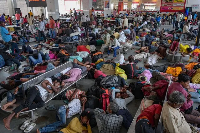 People take rest as they wait for trains at a railway station after rail services disrupted following heavy rainfall in Amritsar on June 11, 2023. (Photo by Narinder Nanu/AFP Photo)