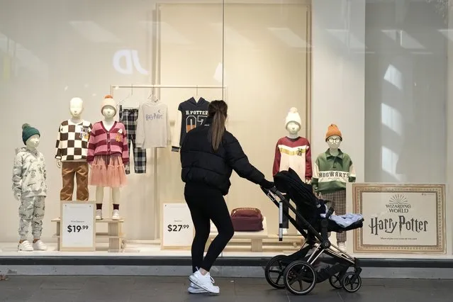A woman pushing a child in a stroller stops to look in a store window in Sydney, Tuesday, May 9, 2023. The Australian government forecast the nation's first balanced annual budget in 15 years but warned that economic pressures such as inflation would push the country into deeper debt in future years. (Photo by Rick Rycroft/AP Photo)
