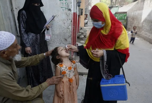 A health worker administers a polio vaccine to a child in Lahore, Pakistan, Monday, March 29, 2021. Despite a steady rise in coronavirus cases, Pakistan on Monday launched a five-day vaccination campaign against polio amid tight security, hoping to eradicate the crippling children's disease this year. (Photo by K.M. Chaudary/AP Photo)