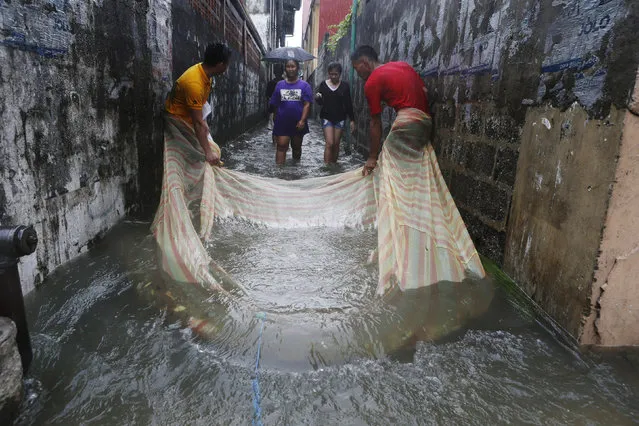 Residents use a mosquito net to catch fish along a flooded alley in a residential district in Bacoor, Cavite near Manila, August 20, 2013. Monsoon rains reinforced by a tropical storm flooded half the Philippine capital in just 24 hours, triggering landslides and killing at least seven people, officials said on Tuesday. (Photo by Erik De Castro/Reuters)