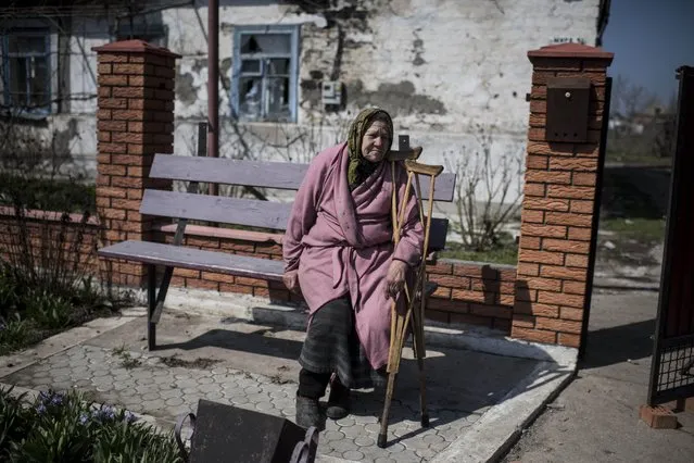 An elderly woman sits in front of her damaged house in the village of Shyrokyne, eastern Ukraine, Thursday, April 16, 2015. Shyrokyne, a village on the Azov Sea that has been the epicenter of recent fighting, has changed hands repeatedly throughout the conflict.  (AP Photo/Evgeniy Maloletka)