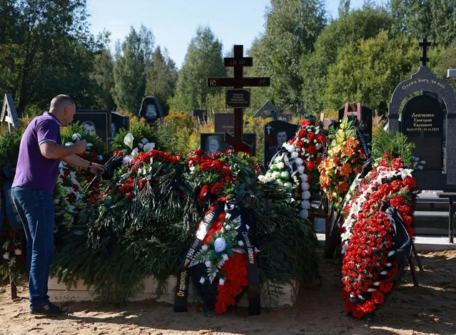 A man outs flowers at the grave of Valery Chekalov, logistics chief of the Wagner private mercenary group, after his funeral at the Severnoye cemetery in Saint Petersburg, Russia on August 29, 2023. (Photo by Reuters/Stringer)