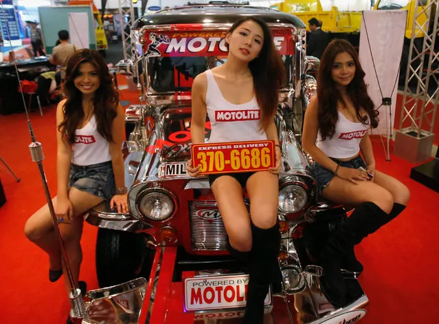 Show promoters for Motolite batteries sit on a jeepney as they pose for photographers during the Manila International Auto show in Pasay, Metro Manila, Philippines on April 4, 2013. (Photo by Erik De Castro/Reuters)