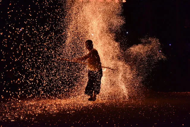 A barefooted man walks through burning charcoal as he performs the traditional ritual called “Lianhuo”, or “fire walking”, on the second day of the May Day holiday on May 2, 2021 in Pan an County, Zhejiang Province of China. (Photo by Kong Debin/VCG via Getty Images)