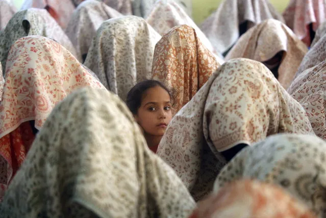 A girl looks on as brides in veils sit on the floor as they wait during a mass marriage ceremony, in Srinagar, the summer capital of Indian Kashmir, 10 September 2023. A total of 100 orphan girls got married during a mass ceremony organized by J&K Al-Noor Yateen (Orphan) Trust to help the economically backward families who cannot afford the high ceremony costs. (Photo by Farooq Khan/EPA)