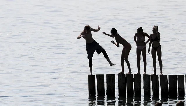 Teens play at a lake in Markkleeberg, eastern Germany, Monday, July 31, 2018. (Photo by Jan Woitas/DPA via AP Photo)