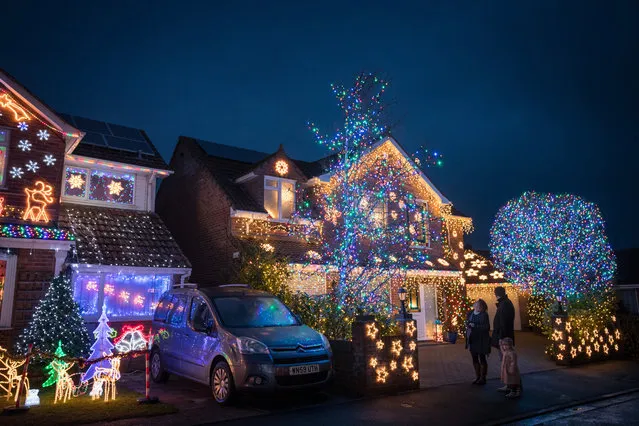 People look at Christmas lights that are displayed on houses in Trinity Close in Burnham-on-Sea on December 8, 2016 in Somerset, England. Since the lights were first turned on ten years ago, the houses in the close have raised tens of thousands of pounds for various charities including a local cancer hospital. The display will be lit every night until January 4th. (Photo by Matt Cardy/Getty Images)