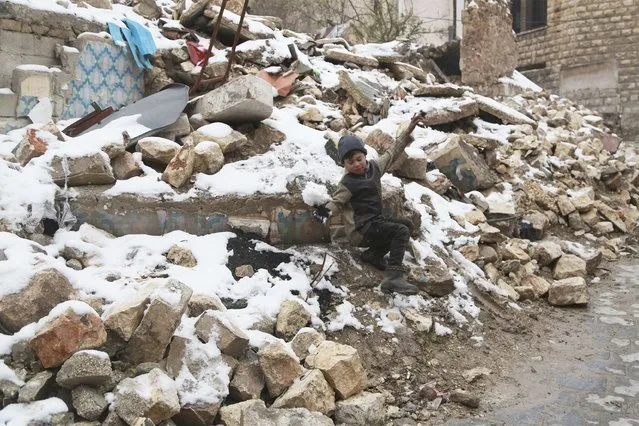 A boy plays with snow on the rubble of collapsed buildings in Aleppo January 12, 2015. (Photo by Nour Kelze/Reuters)