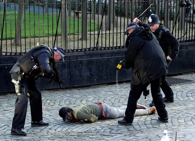 Armed police taser a man inside the grounds of the Houses of Parliament in London, Britain, December 11, 2018. Witnesses reported hearing the man shout: “We're coming for you politicians” as he surged towards the iron gates where PC Palmer was knifed in a terror attack March last year. (Photo by Peter Nicholls/Reuters)