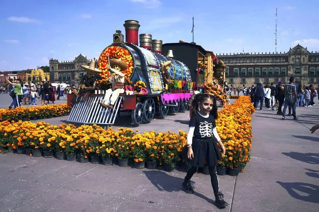 People pose for photos next to a Day of the Dead-themed presentation at  Mexico City´s main square the Zocalo, on Tuesday, Octoner 31, 2023. (Photo by Marco Ugarte/AP Photo)