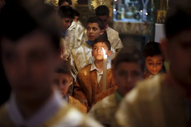A Palestinian boy holds a candle as he attends Orthodox Christian Palm Sunday mass at the Saint Porfirios church in Gaza City April 5, 2015. (Photo by Suhaib Salem/Reuters)