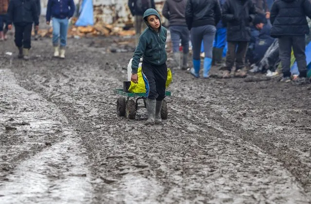 A young migrant pulls a trolley in a muddy field at a camp of makeshift shelters for migrants and asylum-seekers from Iraq, Kurdistan, Iran and Syria, called the Grande Synthe jungle, near Calais, France, February 3, 2016. (Photo by Yves Herman/Reuters)