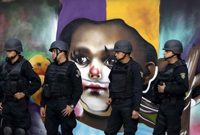 Police providing security walk in front of street art as thousands marched in anger against the government of Enrique Pena Nieto following a 20 percent rise in gas prices, in Mexico City, Monday, January 9, 2017. Demonstrators have been protesting across Mexico since the gasoline price hike took effect on New Year's Day, and the anger has occasionally erupted into violence, including several days of looting last week. (Photo by Rebecca Blackwell/AP Photo)